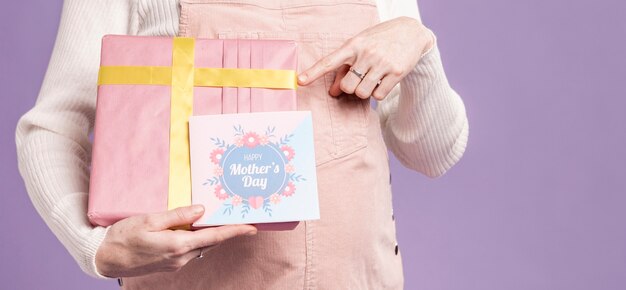 Primer plano mujer embarazada apuntando a regalo y tarjeta de felicitación