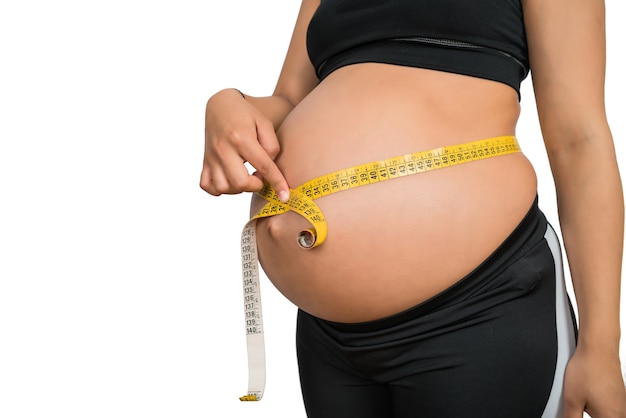 Primer plano de una mujer embarazada con cinta métrica para controlar el desarrollo del bebé