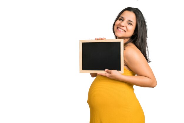 Primer plano de mujer embarazada sosteniendo y mostrando algo en la pizarra. Concepto de anuncio de embarazo, maternidad y promoción.