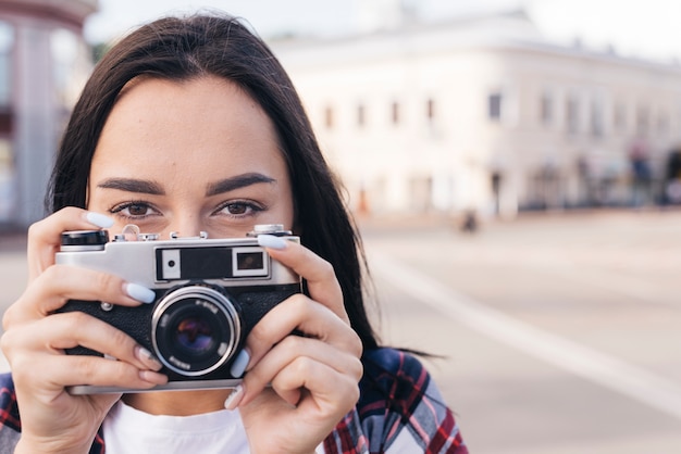 Primer plano de mujer escondiendo la boca con la celebración de cámara retro