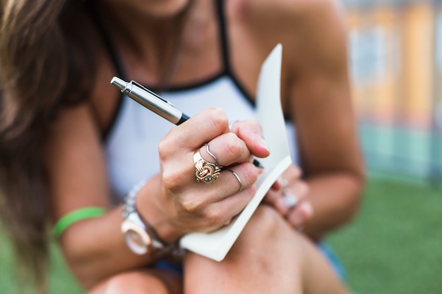 Primer plano de mujer escribiendo en cuaderno con pluma