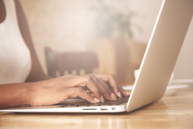 Primer plano de una mujer escribiendo en el teclado del portátil