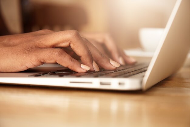 Primer plano de una mujer escribiendo en el teclado del portátil