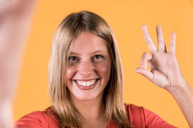 Foto gratuita primer plano de una mujer feliz mostrando gesto bien sobre fondo de estudio