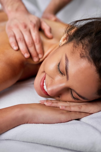 Foto gratuita primer plano de una mujer feliz con los ojos cerrados disfrutando de un masaje de espalda en el spa
