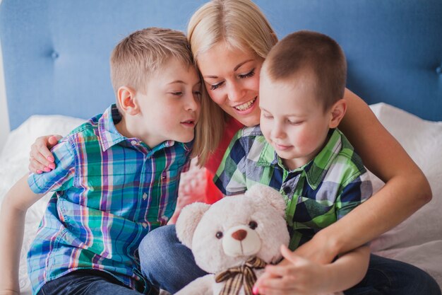 Primer plano de mujer feliz con sus hijos y un oso de peluche