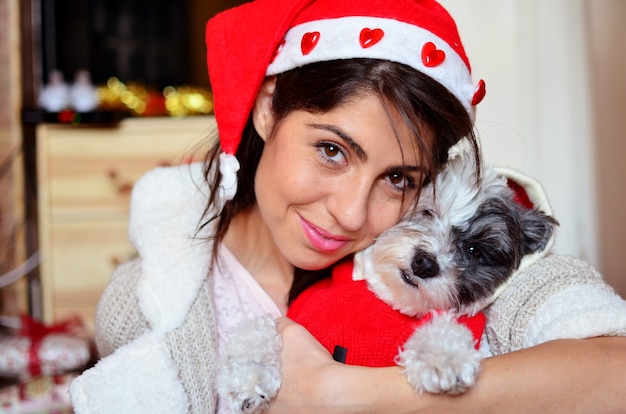 Primer plano de mujer con gorro de santa posando con su perro