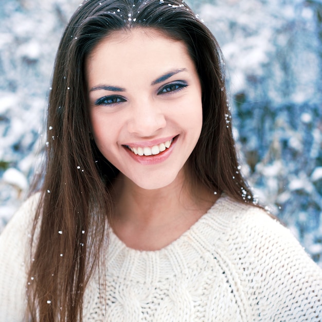 Primer plano de mujer con una gran sonrisa y copos de nieve en la cabeza