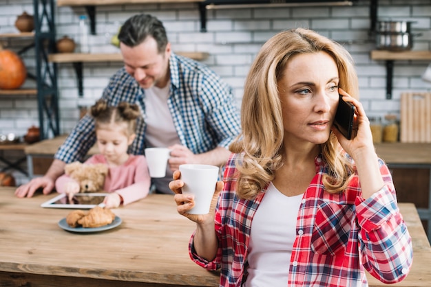 Primer plano de una mujer hablando por celular sosteniendo una taza de café