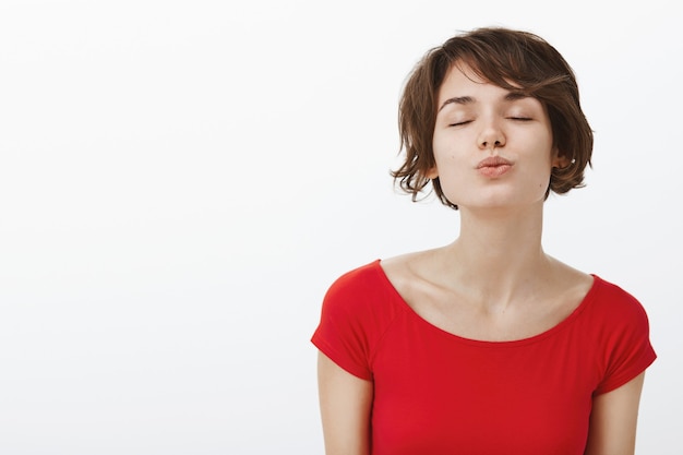 Primer plano de mujer hermosa romántica cerrar los ojos y hacer pucheros, esperando un beso