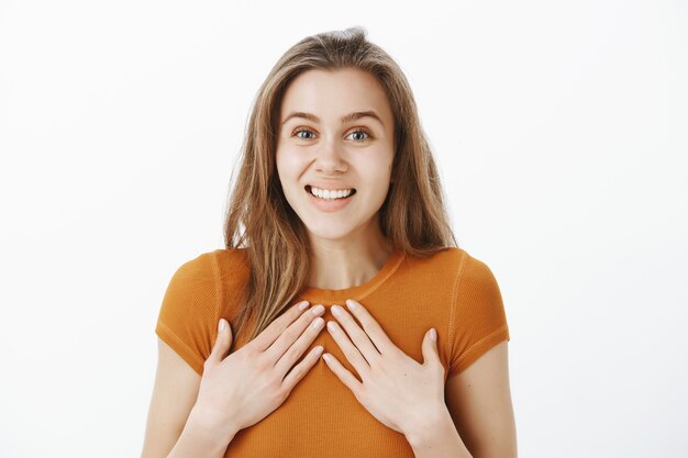 Primer plano de mujer hermosa sorprendida y emocionada, tomados de la mano en el pecho halagado