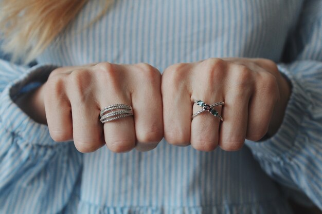 Primer plano de una mujer con hermosos anillos en ambas manos y mostrando con los puños