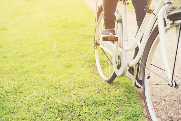 Foto gratuita primer plano de una mujer inconformista joven con su pie sobre la bicicleta peda