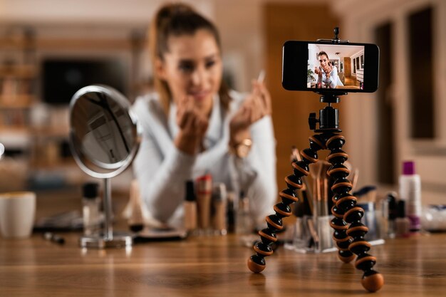 Primer plano de una mujer influyente transmitiendo en vivo sobre productos de belleza en casa