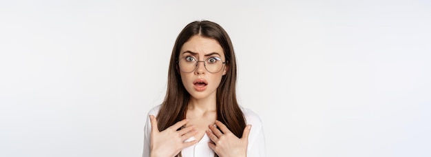 Foto gratuita primer plano de una mujer insultada conmocionada con gafas que parece herida y confundida de pie sobre un fondo blanco