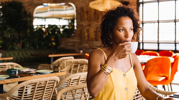 Primer plano de una mujer joven afroamericana tomando café