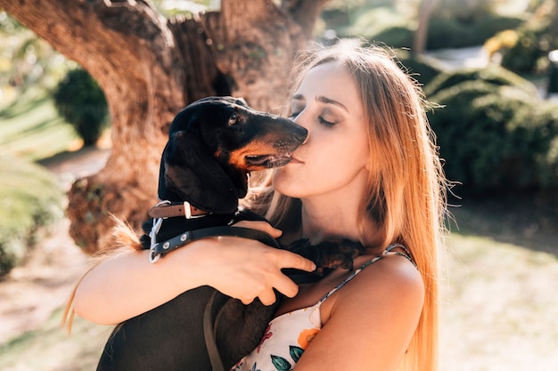 Primer plano de una mujer joven besando a su mascota