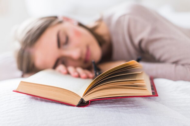 Primer plano de mujer joven durmiendo con el libro en la cama