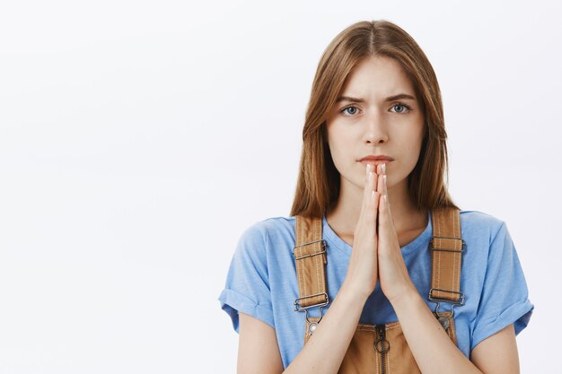 Primer plano de mujer joven esperanzada rezando, suplicando a Dios, pidiendo ayuda