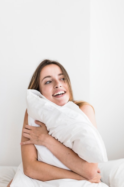 Primer plano de una mujer joven feliz abrazando la almohada