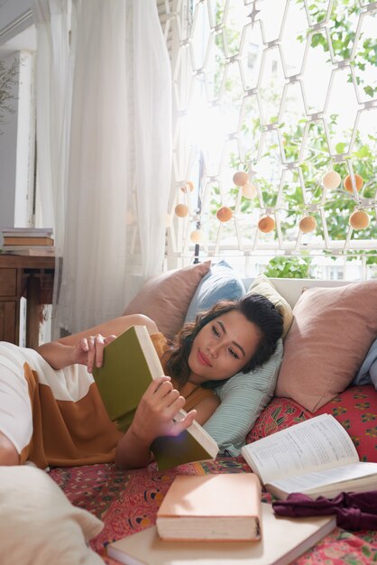 Primer plano de una mujer joven leyendo un libro en la cama