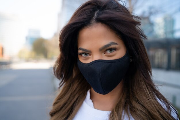 Primer plano de una mujer joven con mascarilla mientras está de pie al aire libre en la calle. Concepto urbano. Nuevo concepto de estilo de vida normal.