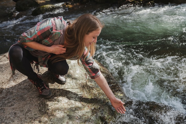 Primer plano de mujer joven mojando su mano en el río