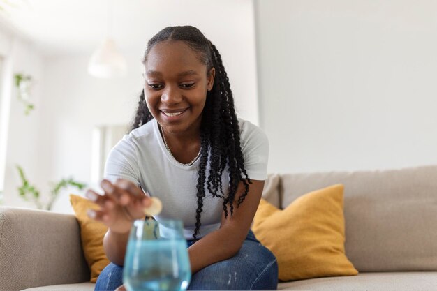 Primer plano de una mujer joven que deja caer un antiácido efervescente en un vaso de agua mujer joven apenas pone una pastilla soluble con un medicamento para el dolor o la resaca en un vaso de agua