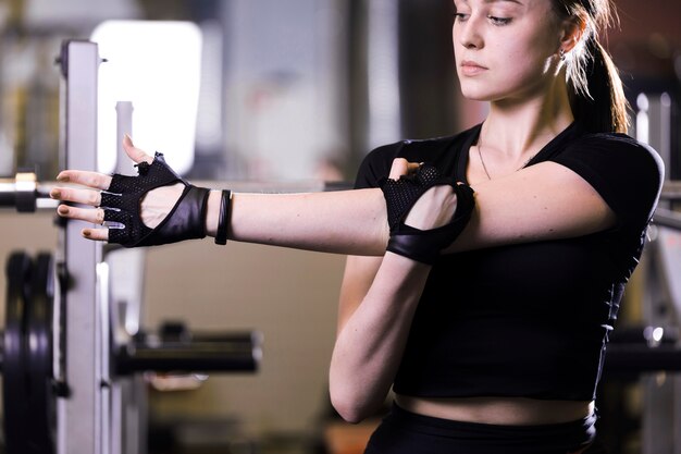 Primer plano de una mujer joven que estira sus brazos en gimnasio