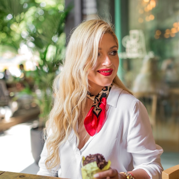 Foto gratuita primer plano de mujer joven rubia con muffin en la mano