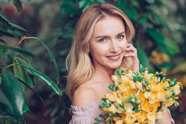 Primer plano de mujer joven rubia con ramo de flores amarillas