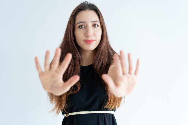 Primer plano de mujer joven sonriente que muestra gesto de parada