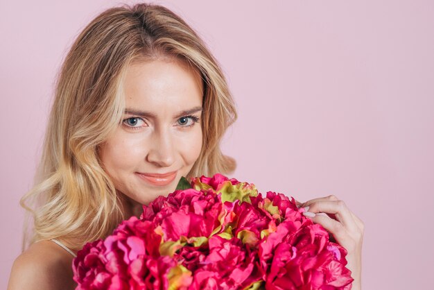 Primer plano de mujer joven sonriente con ramo de flores rosa