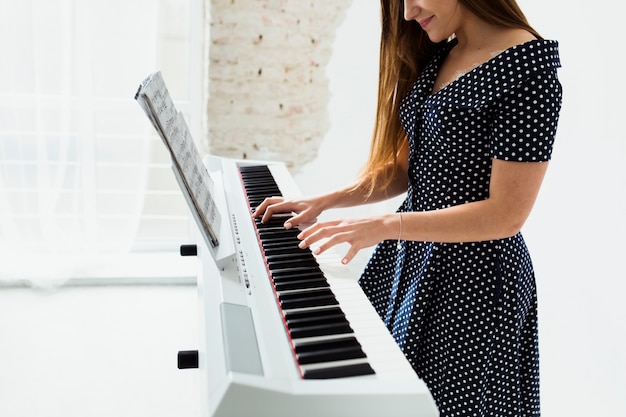 Primer plano de mujer joven sonriente tocando el piano