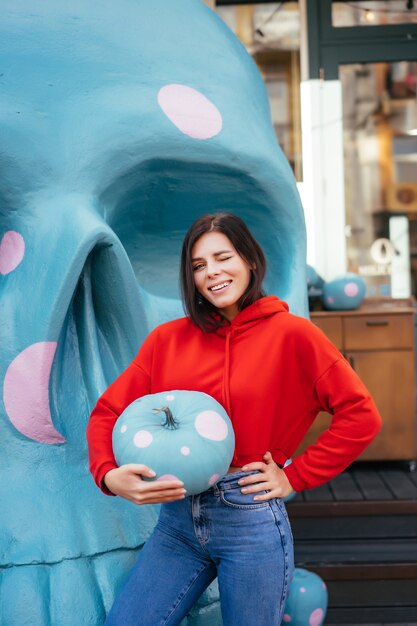 Primer plano de una mujer joven sosteniendo una calabaza ornamentada de color azul en manchas blancas