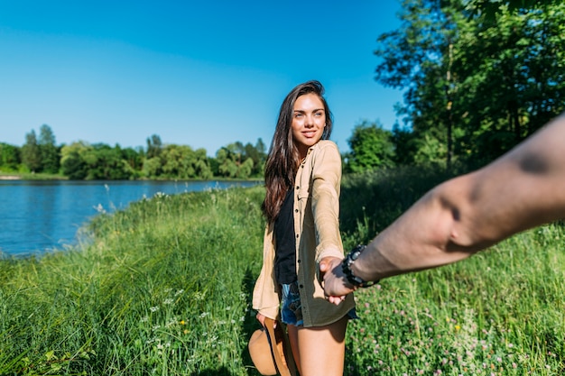 Foto gratuita primer plano de mujer joven sosteniendo la mano del hombre mientras lo conduce a la naturaleza al aire libre