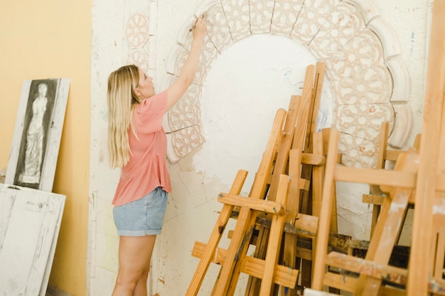 Primer plano, de, mujer joven, talla, en, pared, con, herramientas