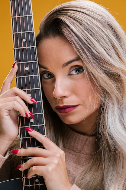 Foto gratuita primer plano, de, mujer joven, tenencia, guitarra