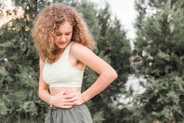 Primer plano, de, mujer joven, teniendo, dolor, en, ella, cintura