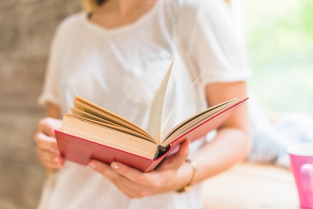 Primer plano de mujer con libro de tapa roja en las manos