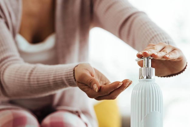 Primer plano de una mujer limpiándose las manos con gel antiséptico para manos en casa