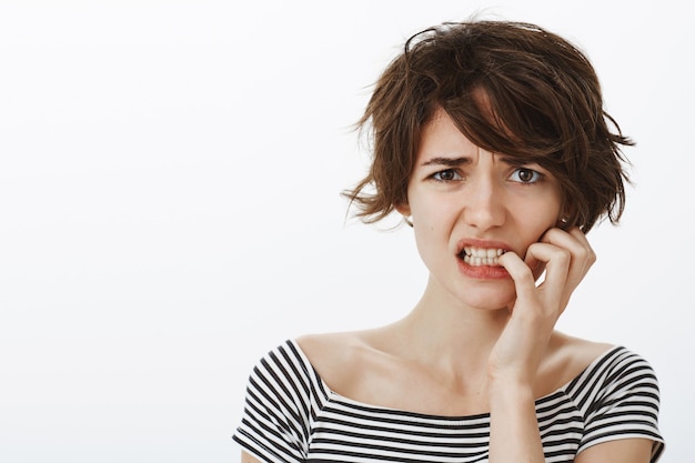 Primer plano de mujer linda preocupada y culpable haciendo muecas nerviosamente