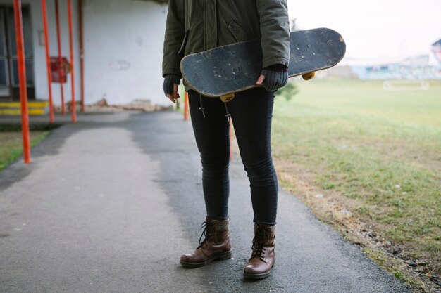 Primer plano de una mujer llevando patineta en mano