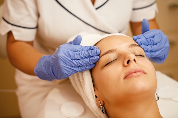 Primer plano de mujer con masaje facial durante el tratamiento de belleza en el spa