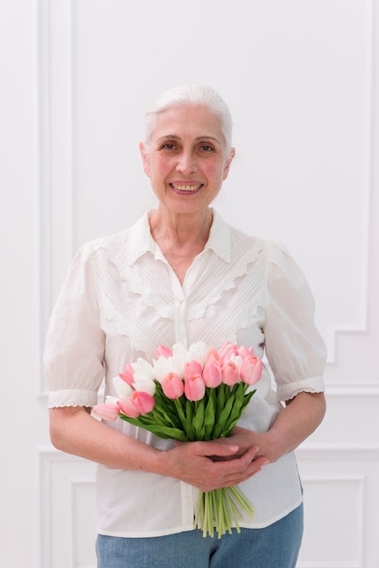 Foto gratuita primer plano de una mujer mayor con ramo de flores de tulipán mirando a cámara