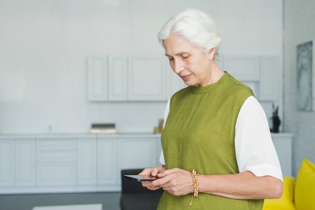 Foto gratuita primer plano, de, mujer mayor, usar, móvil, en casa