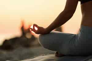 Foto gratuita primer plano de mujer meditando en posición de loto al atardecer.