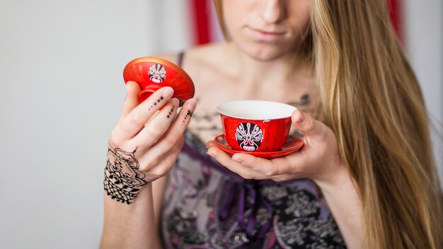 Primer plano de una mujer mirando el té tradicionalmente preparado en la taza