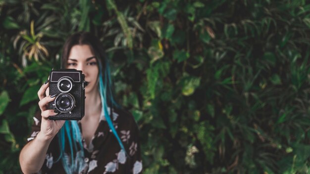 Primer plano de mujer moderna tomando foto con cámara vintage