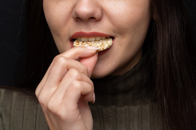 Primer plano de una mujer mordiendo una galleta bajo las luces